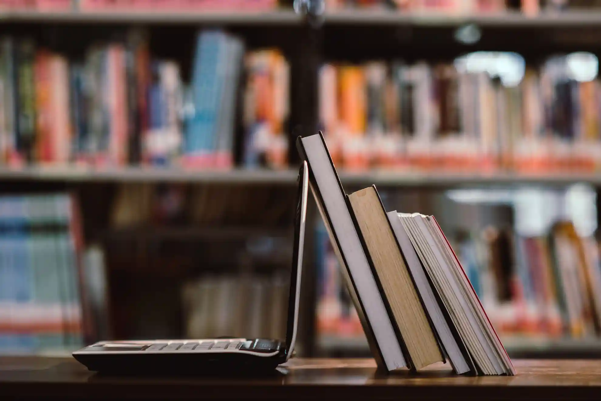 Ordinateur portable ouvert sur un bureau avec des livres et une bibliothèque en fond, illustrant le blog de TeA Formations consacré à Linux et aux technologies open source